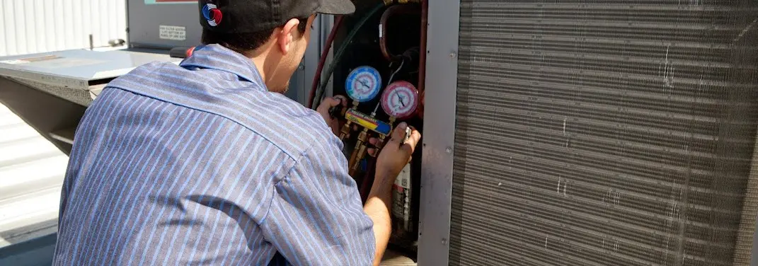 HVAC technician servicing a condenser unit in Plainfield